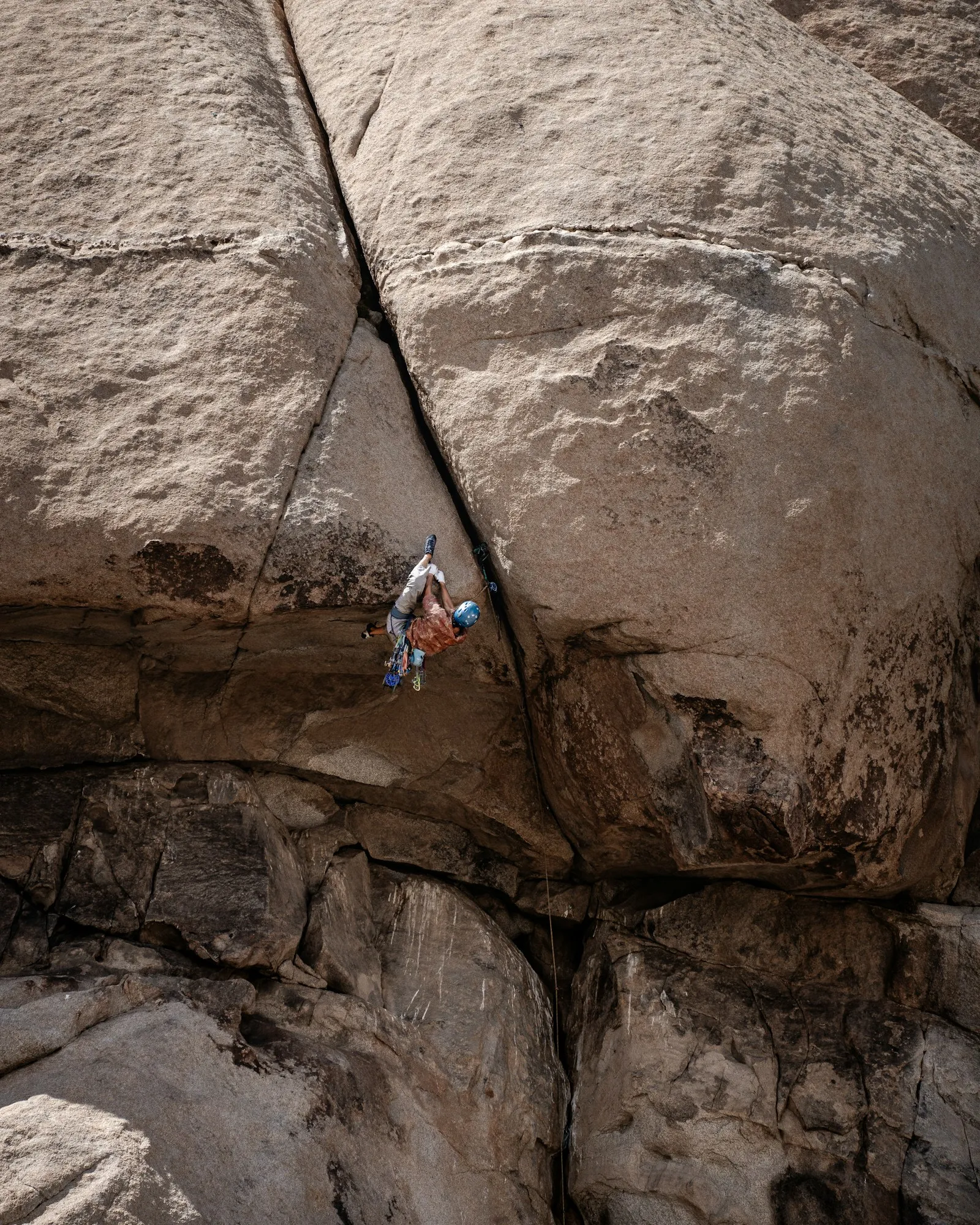 A climber reaching for a hold on a granite face